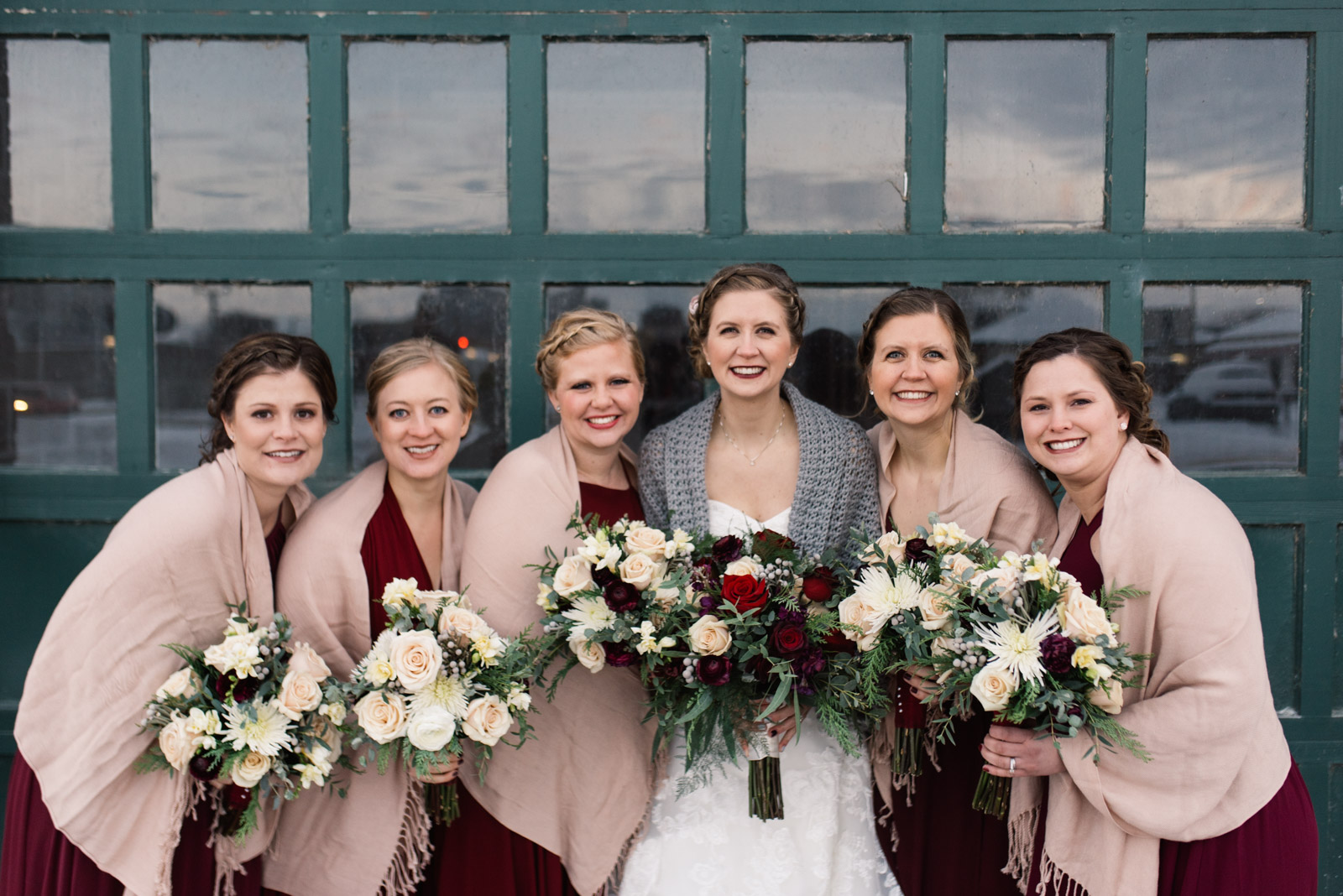 bride and bridesmaids holding flowers in front of green door cedar rapids newbo wedding