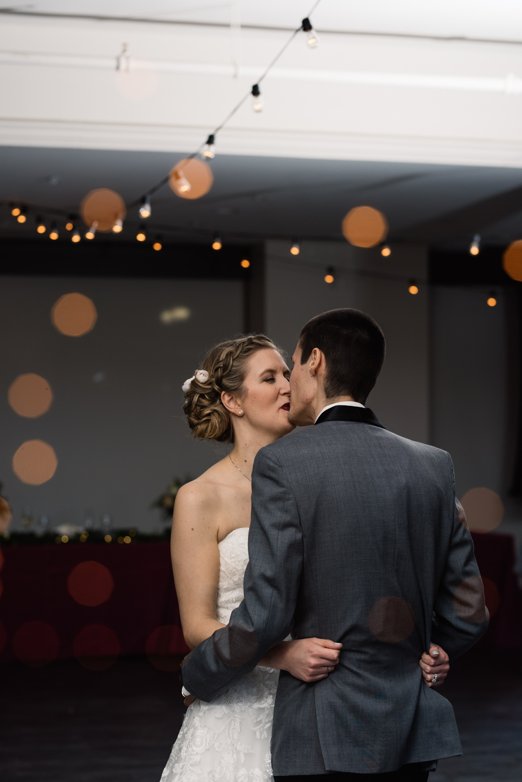 bride and groom kissing under string lights eastbank wedding venue