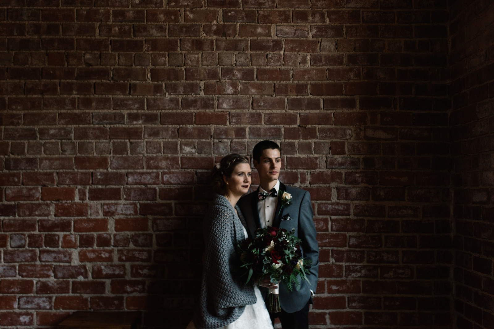 bride and groom next to brick wall black sheep social club winter wedding