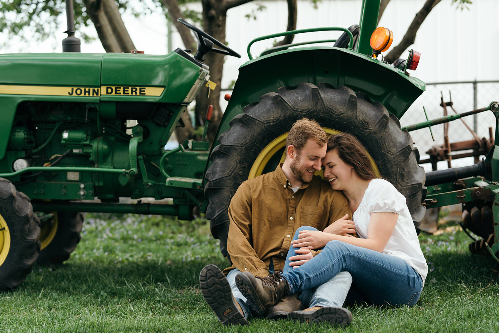 engaged couple cuddling tractor wellman iowa engagement session