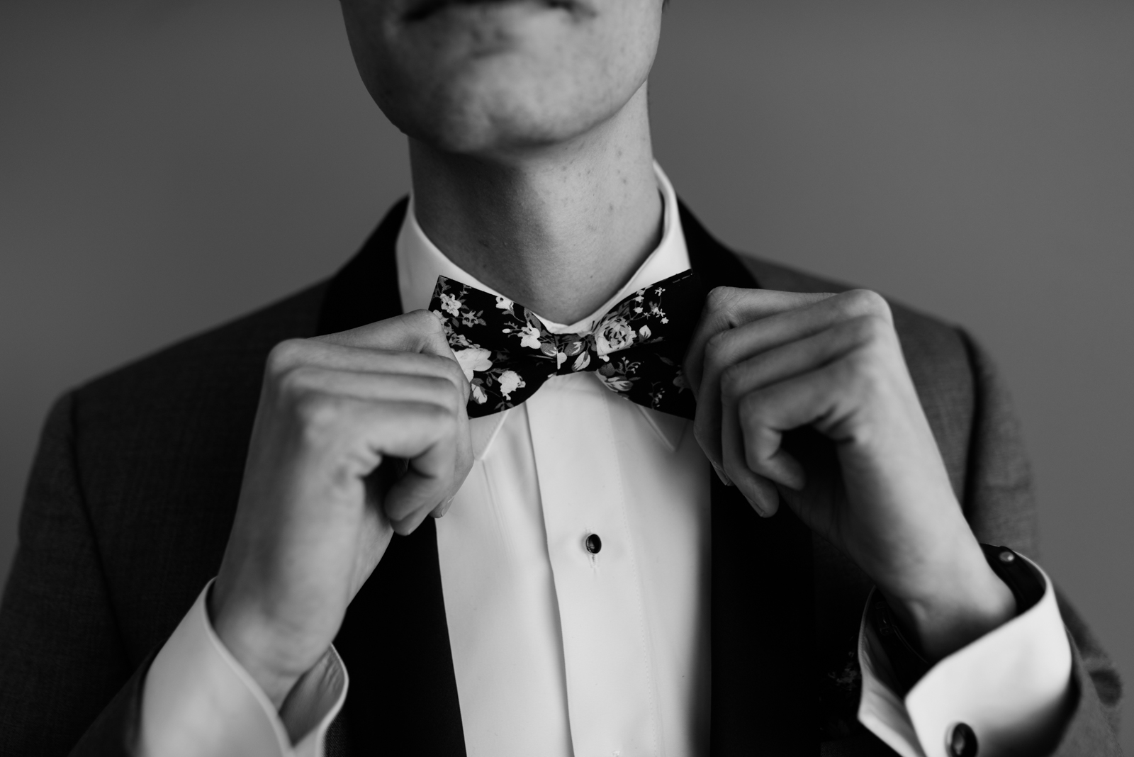 groom adjusting floral bow tie