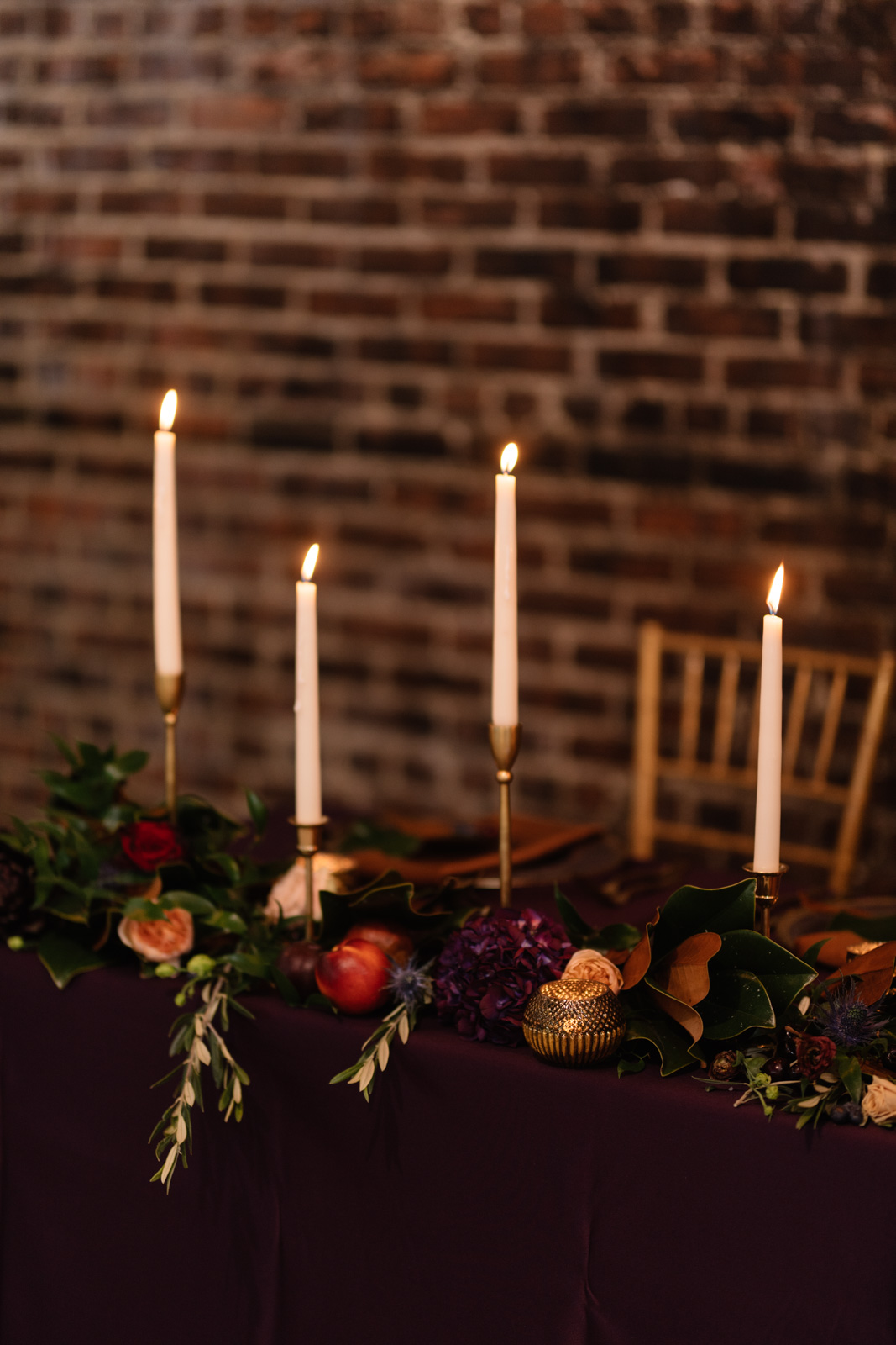 candle lit head table by unique events brick wall the olympic south side theater wedding venue