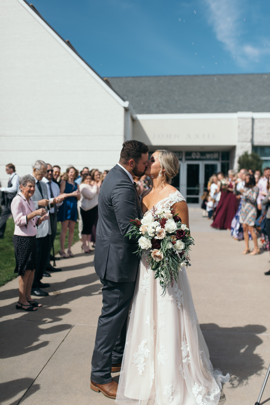 bride and groom kissing outside St. John XXIII Parish wedding