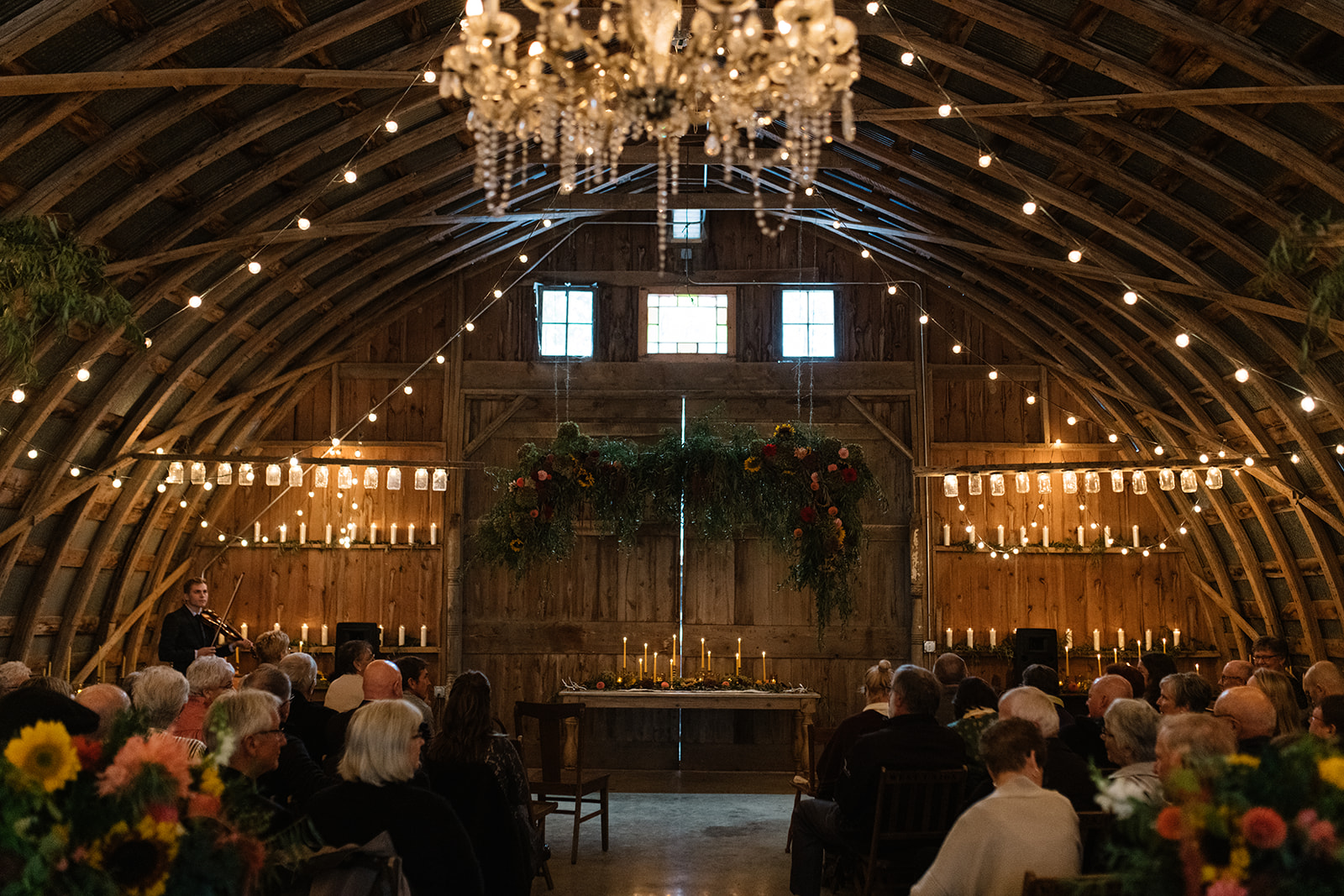 Wedding Ceremony with string lights at The Barn Wellman Iowa Wedding Venue inside