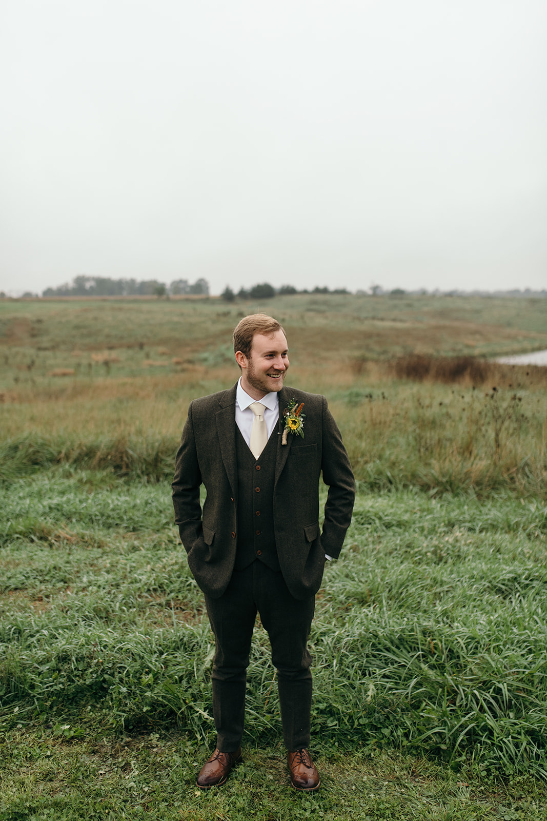 groom standing in field tweed suit iowa fall wedding