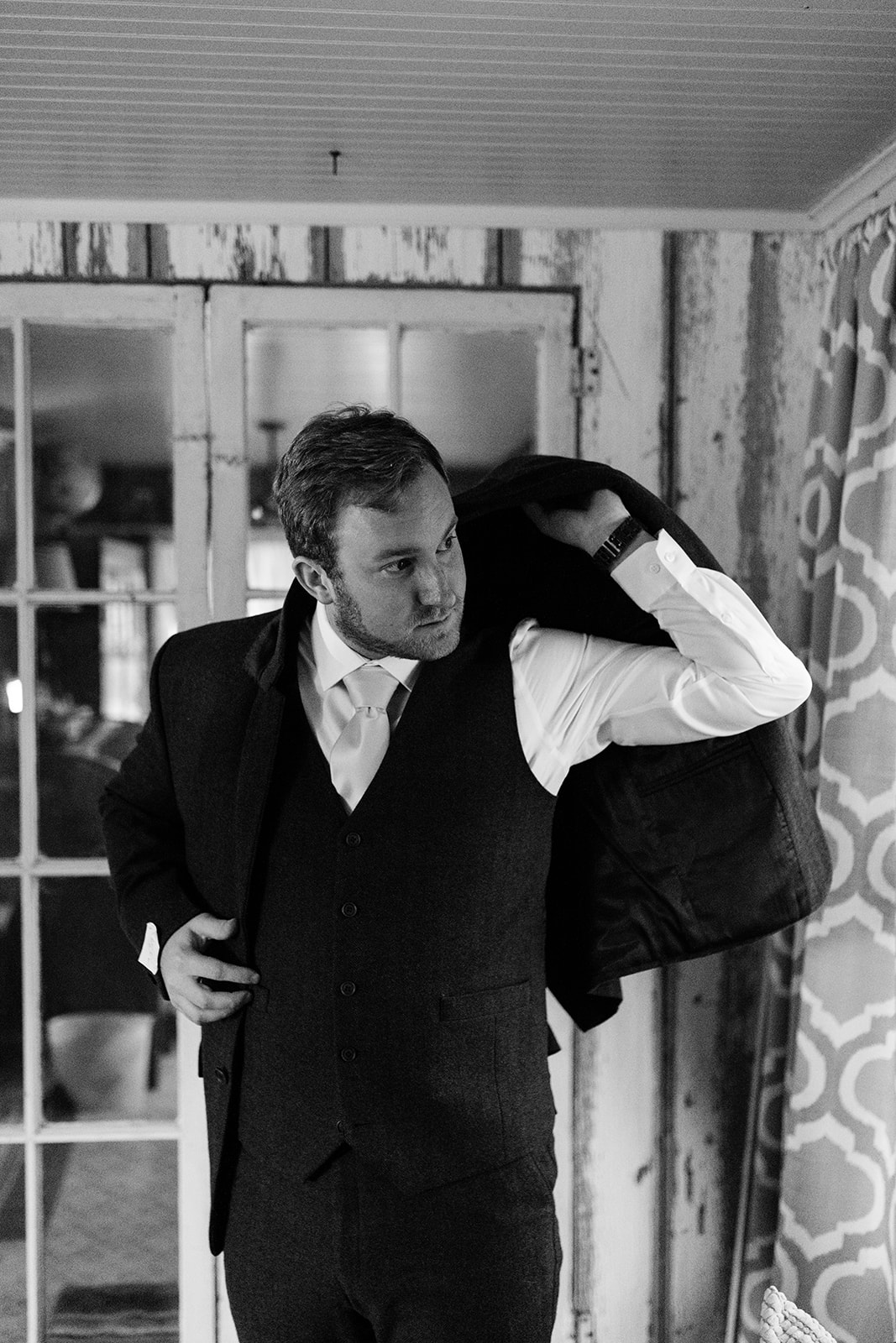 groom putting on suit jacket iowa wedding