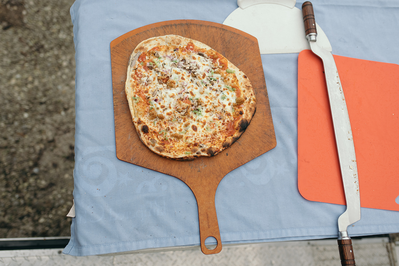 brick oven pizza on cutting board above Stone Wall Pizza wedding