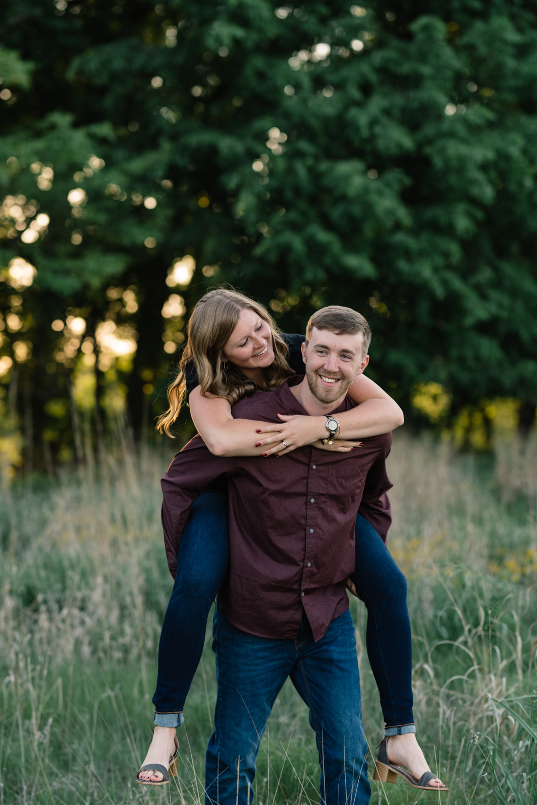 couple piggy back ride in field sunset george wyth state park engagement session