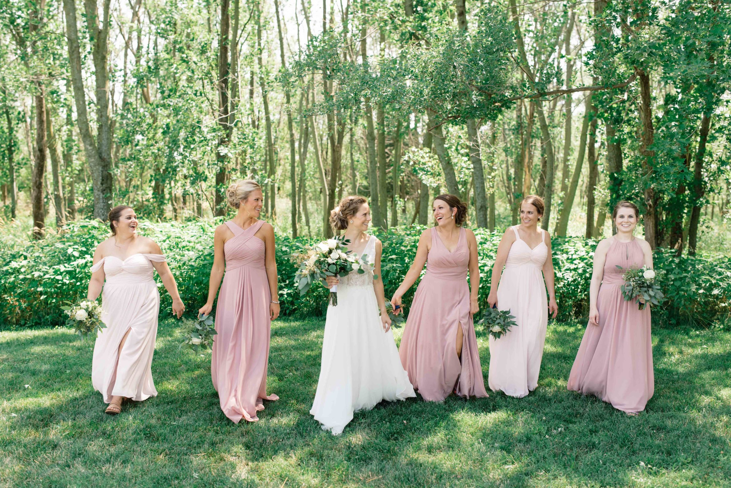 bridesmaid in blush pink dresses walking in forest schafer century barn wedding venue