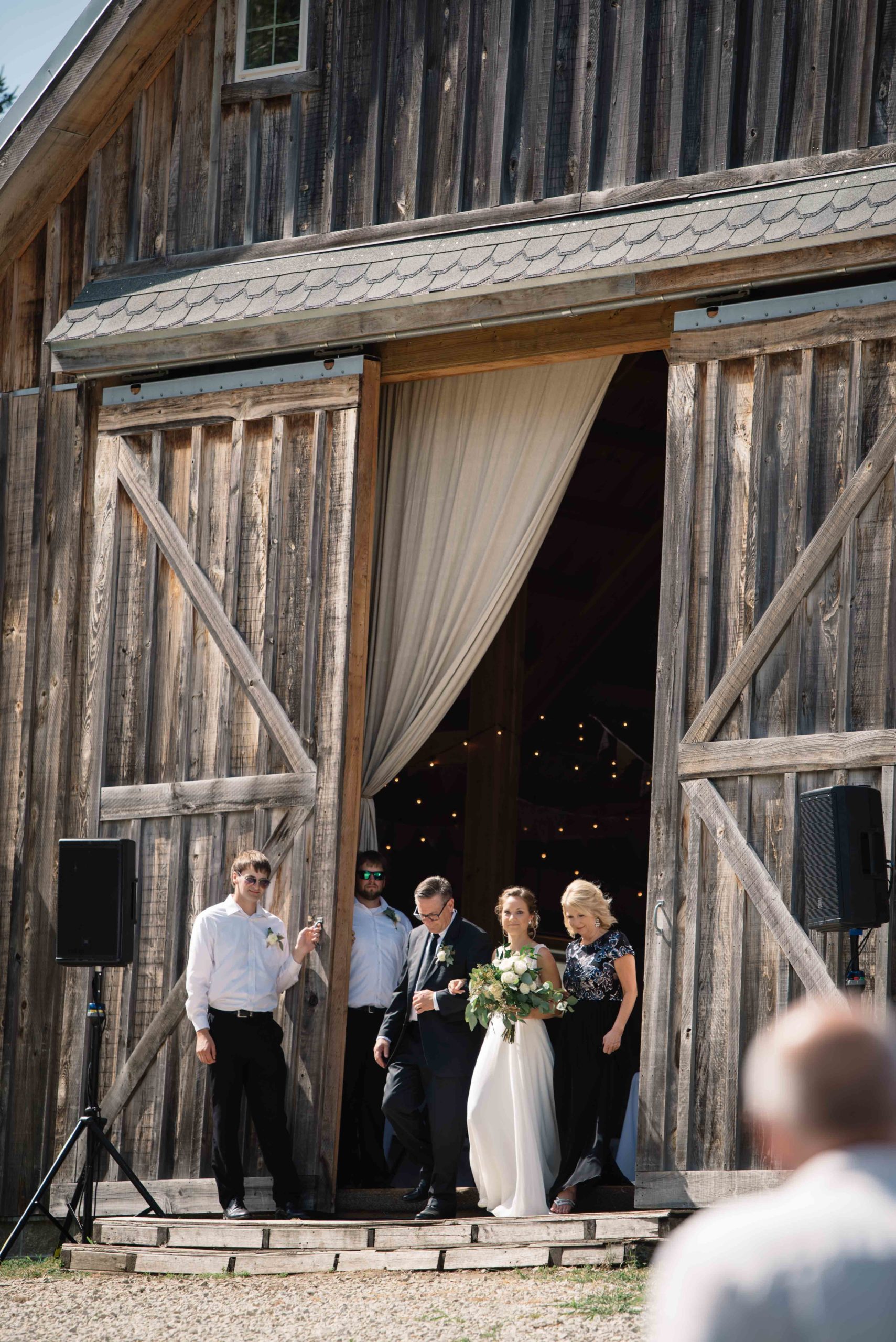 barn doors opening to reveal bride for outdoor Iowa barn wedding ceremony