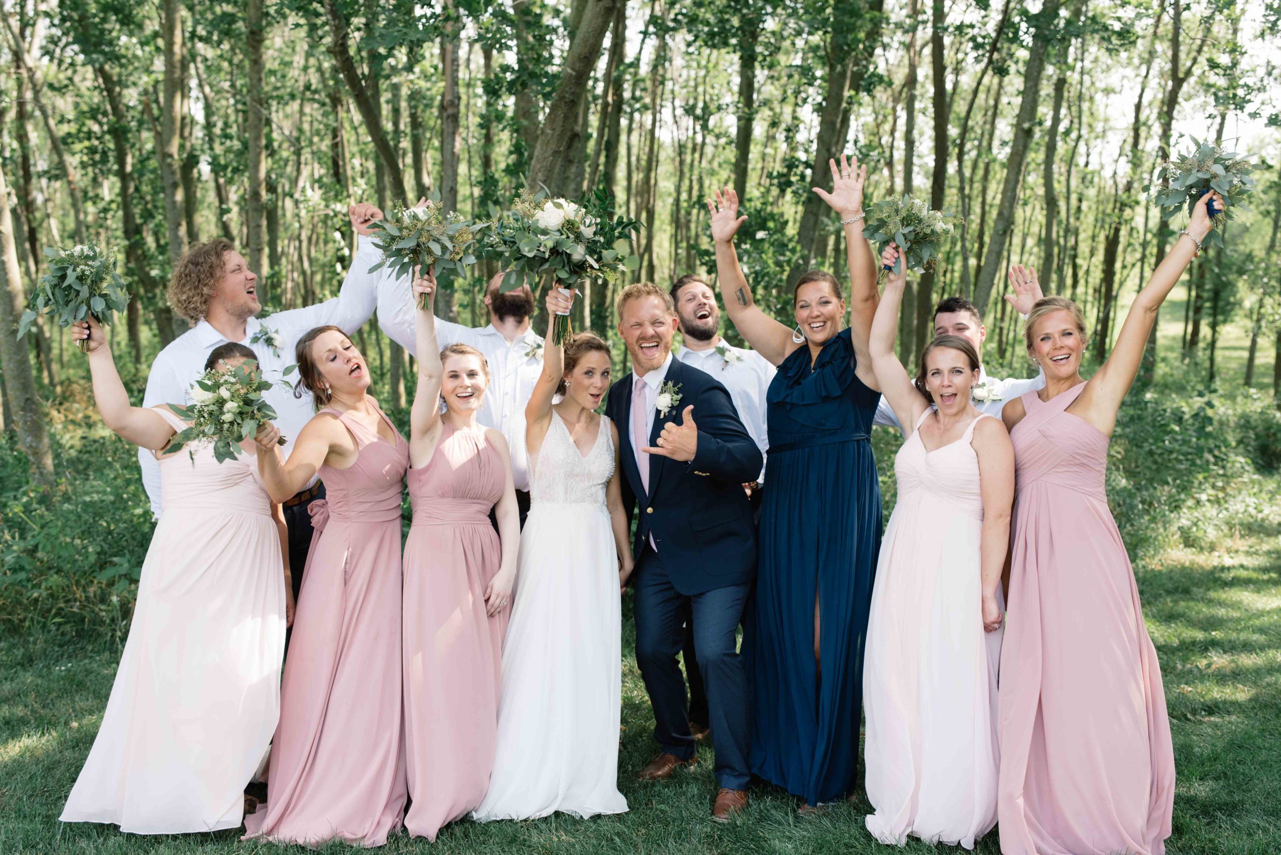 bridal party cheering as bride and groom kiss schafer century barn iowa wedding venue