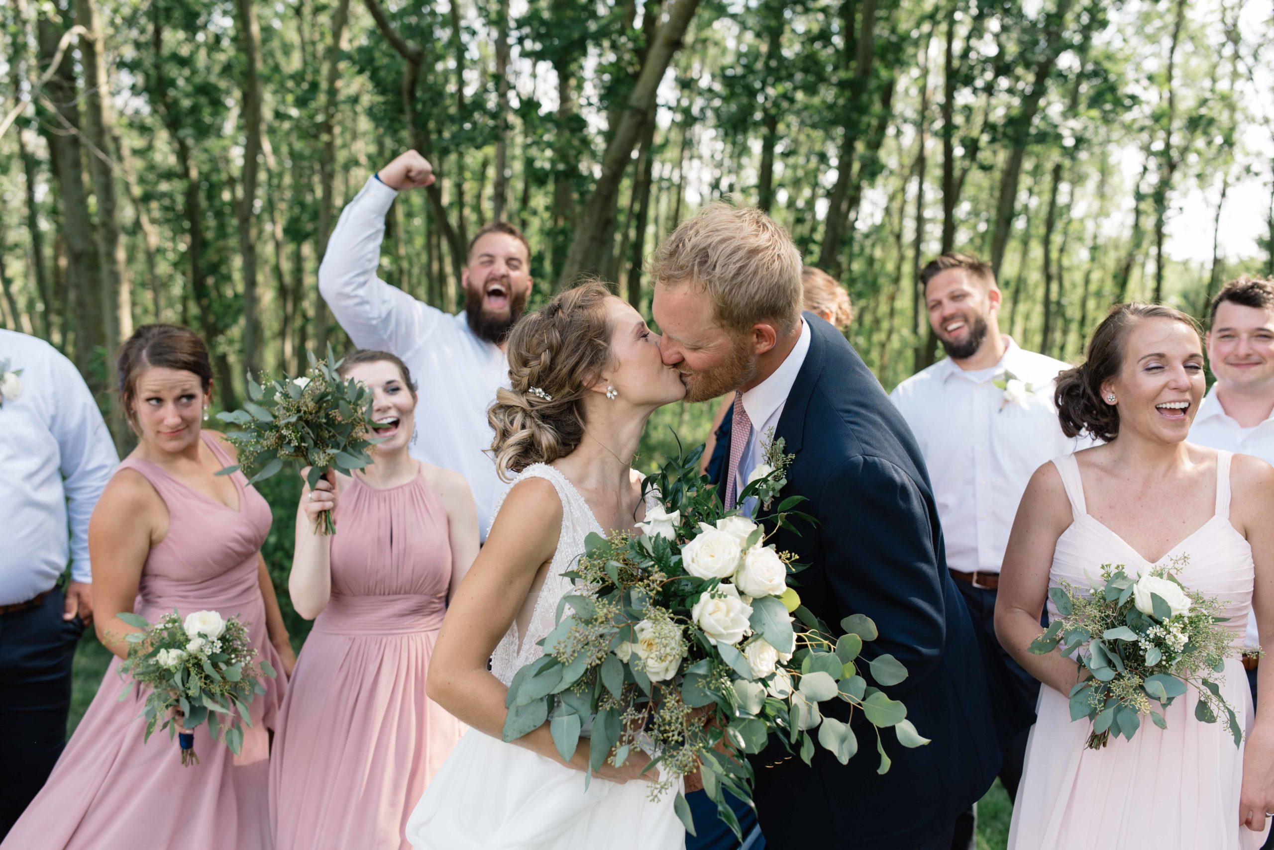 bridal party cheering as bride and groom kiss schafer century barn iowa wedding venue