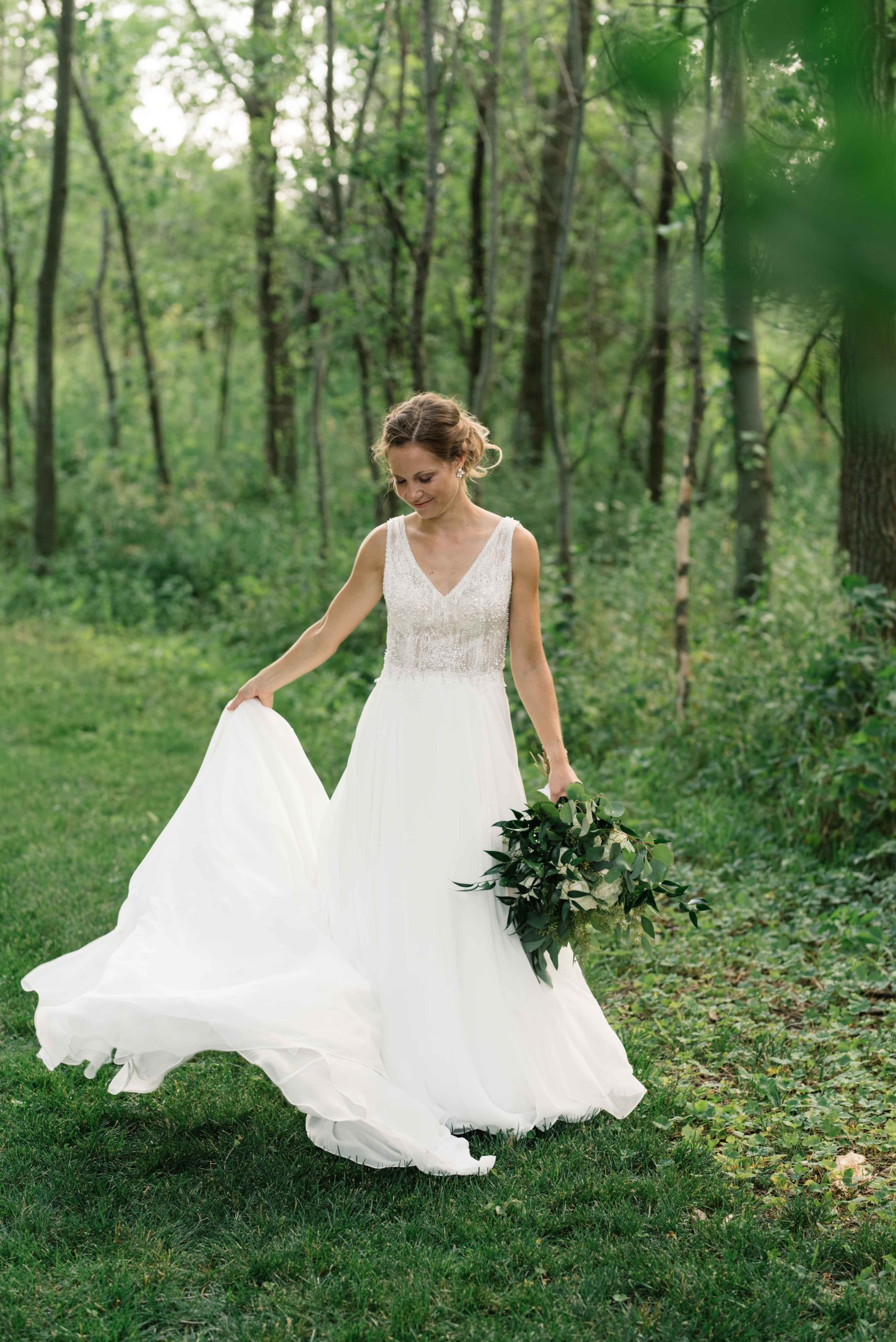 bride twirls in wedding dress under green trees schafer century barn wedding venue