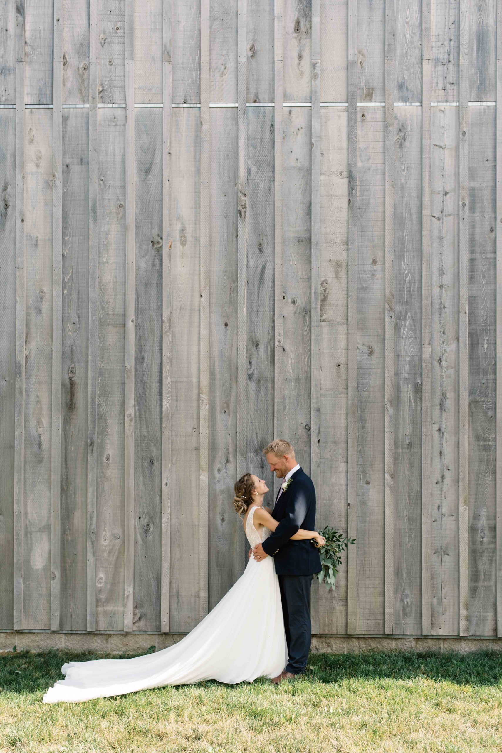 bride and groom in front of gray barn schafer century barn wedding venue