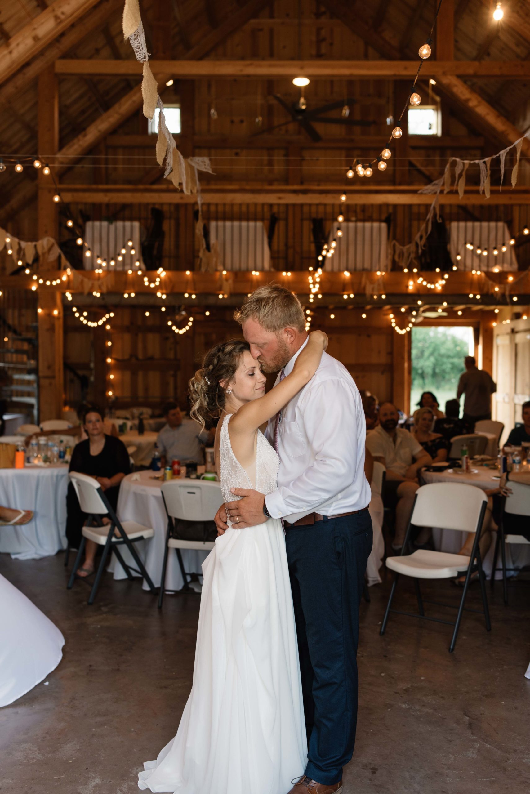 bride and groom first dance under twinkly edison bulb lights schafer century barn wedding venue