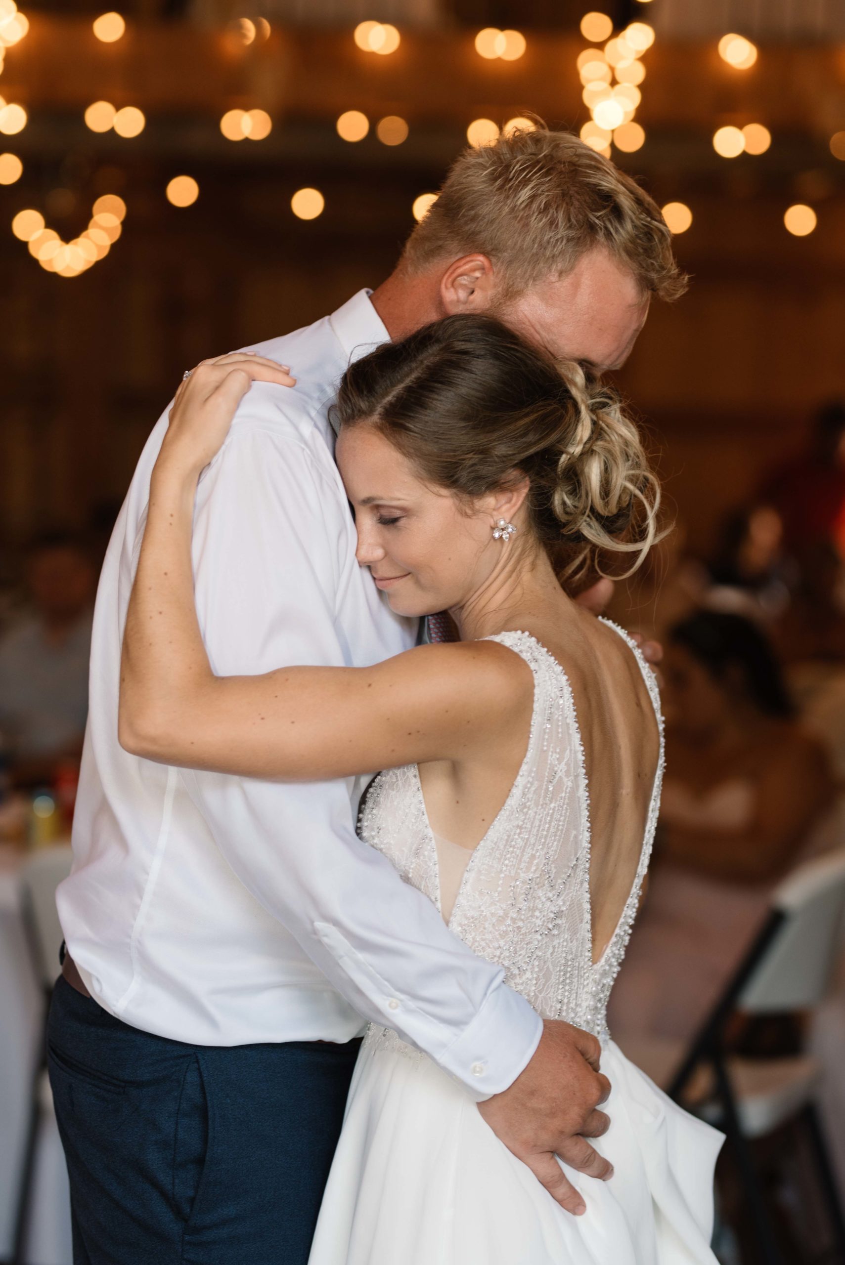 bride and groom first dance under twinkly edison bulb lights schafer century barn wedding venue