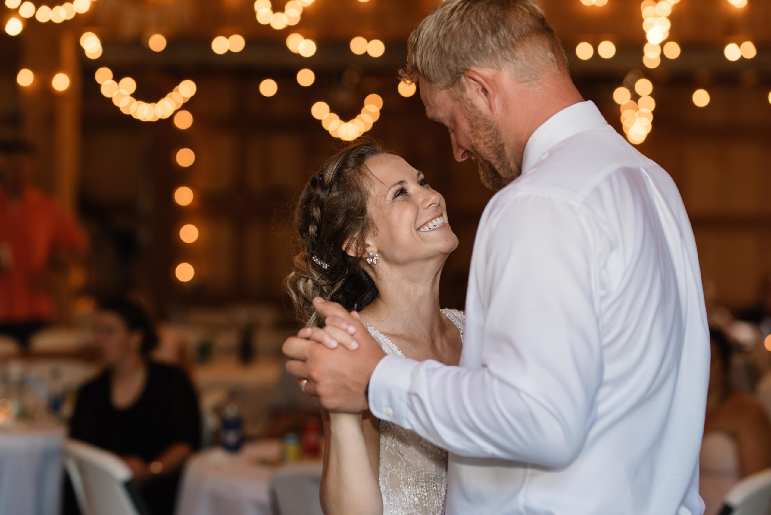 bride and groom first dance under twinkly edison bulb lights schafer century barn wedding venue