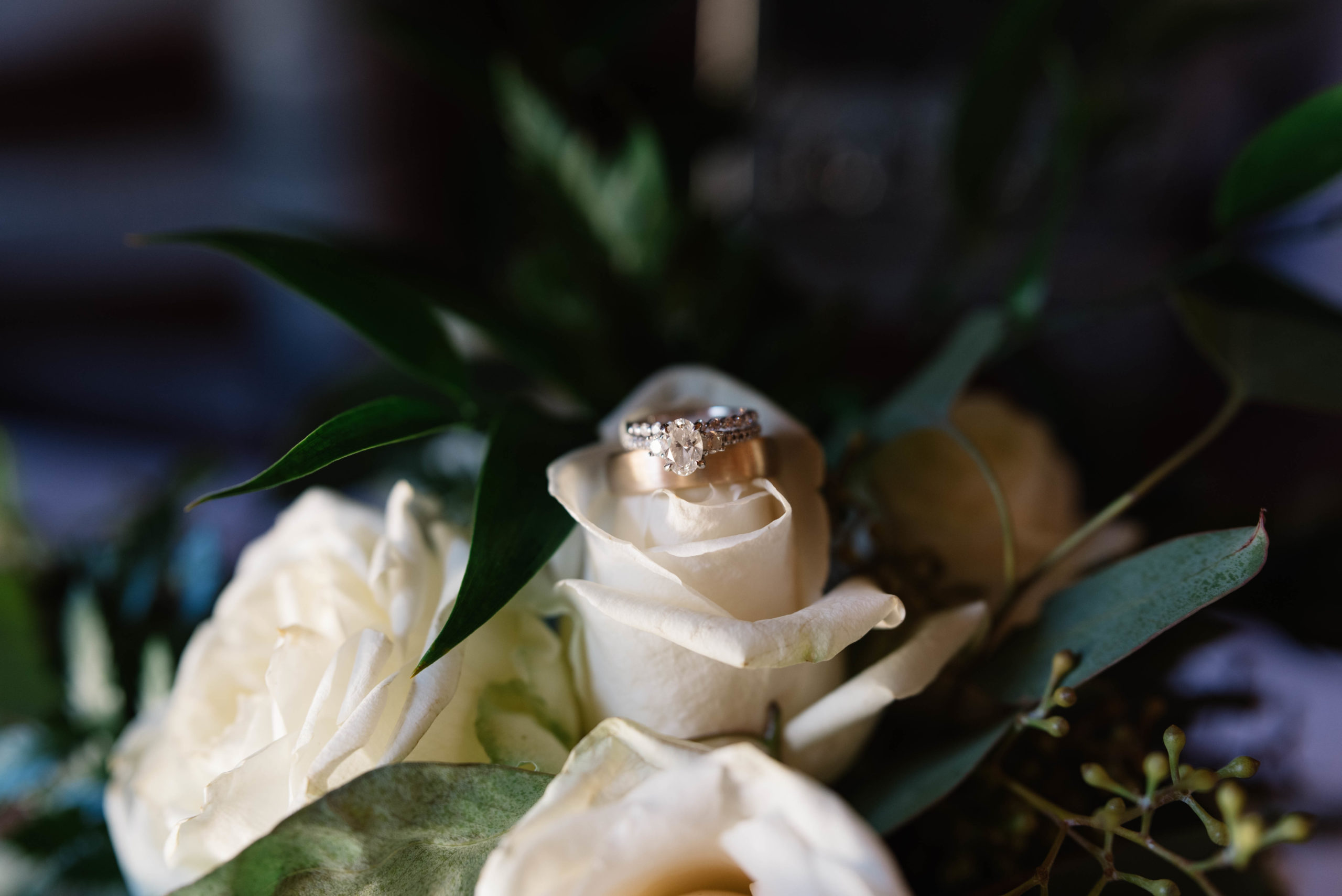 wedding rings on white rose wedding bouquet