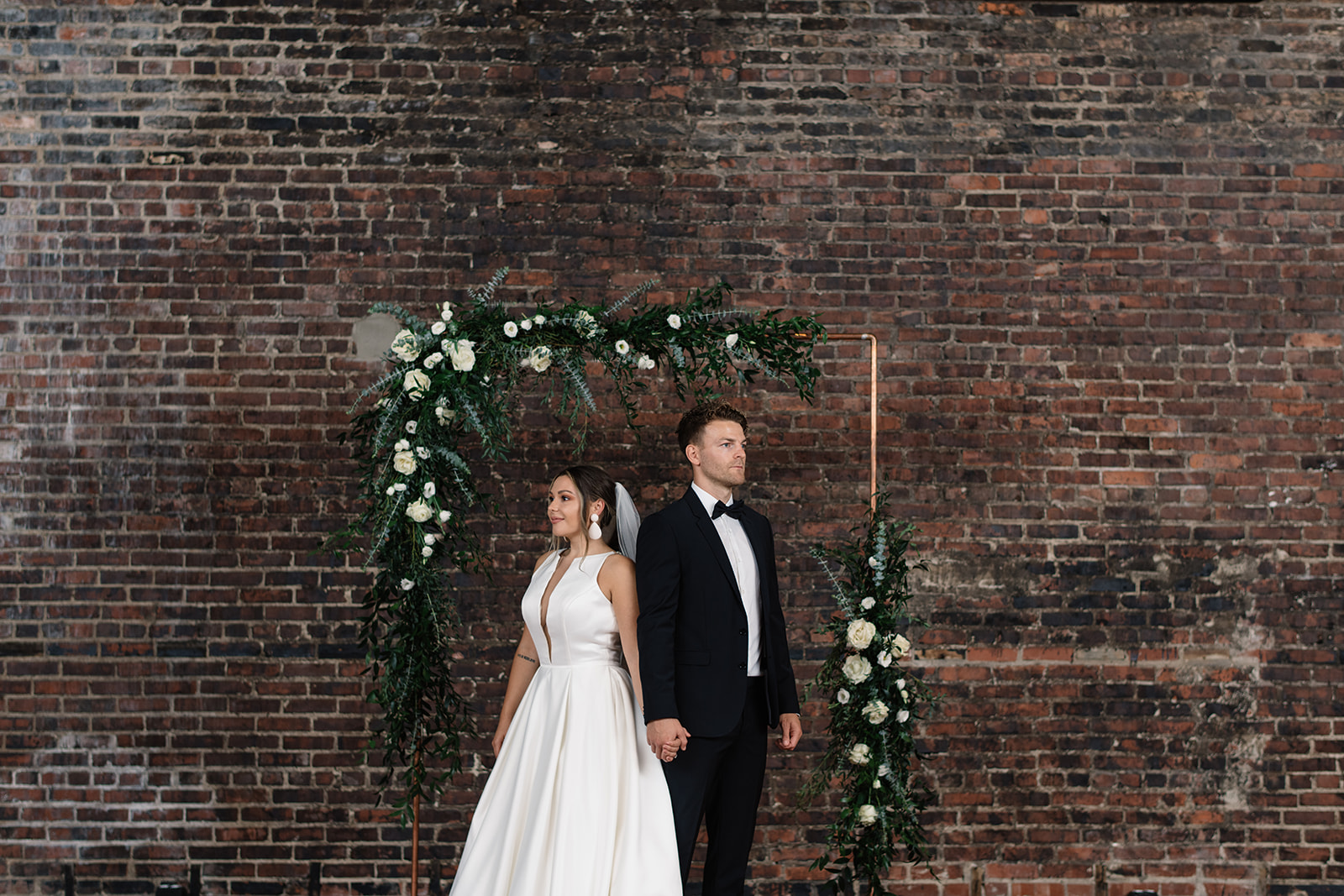 bride and groom under white rose greenery copper arbor olympic south side theater wedding venue