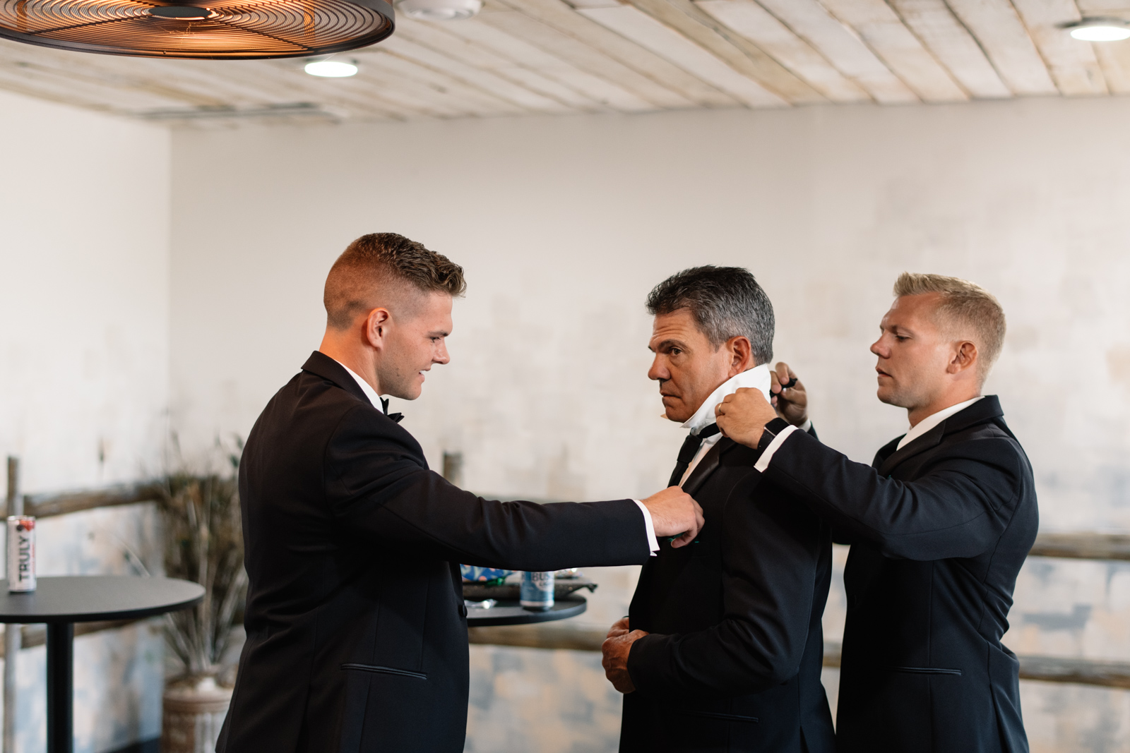 groom and best man helping father of the groom tie tie